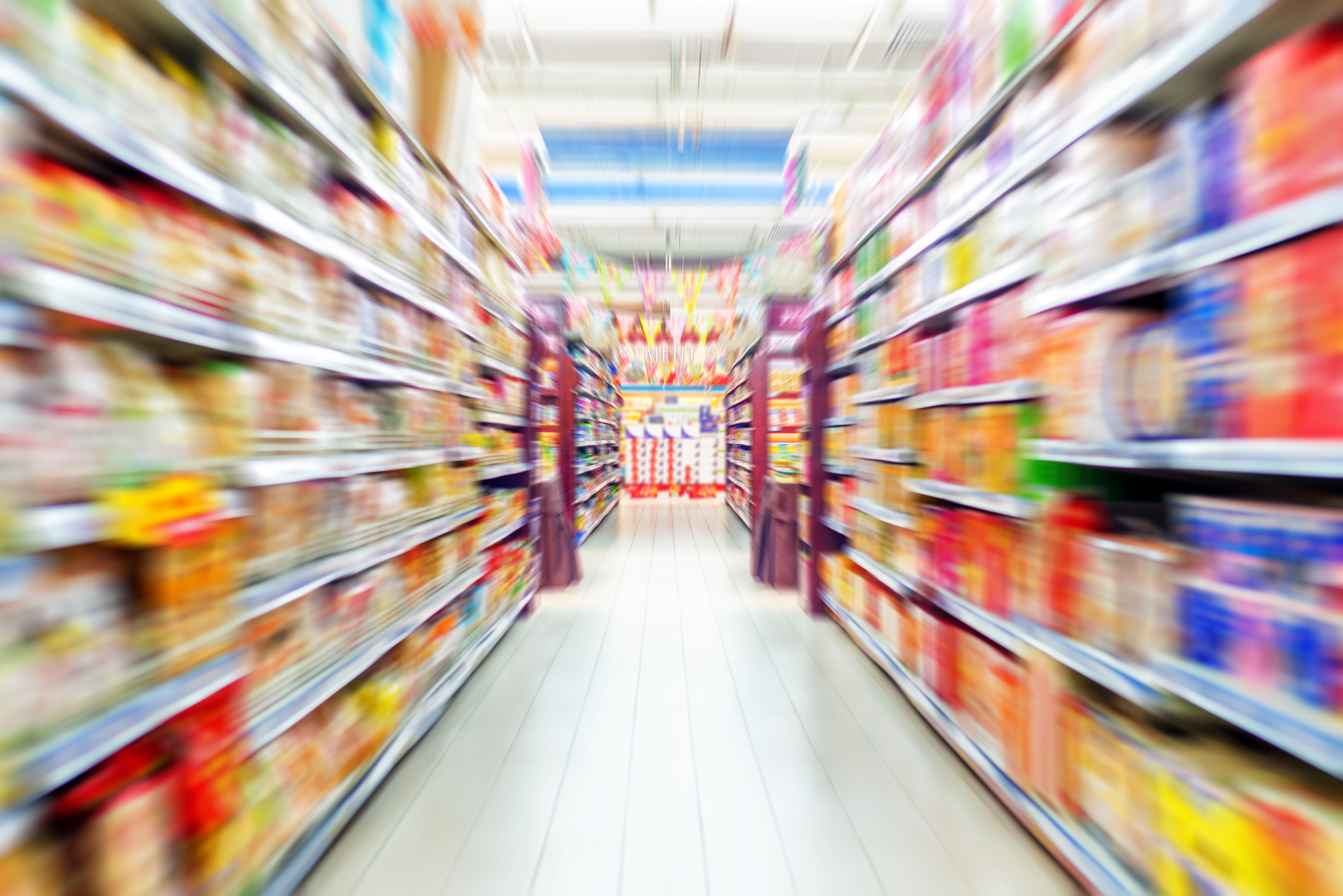 supermarket aisle with colorful product shelves on both sides; a bright, busy atmosphere.